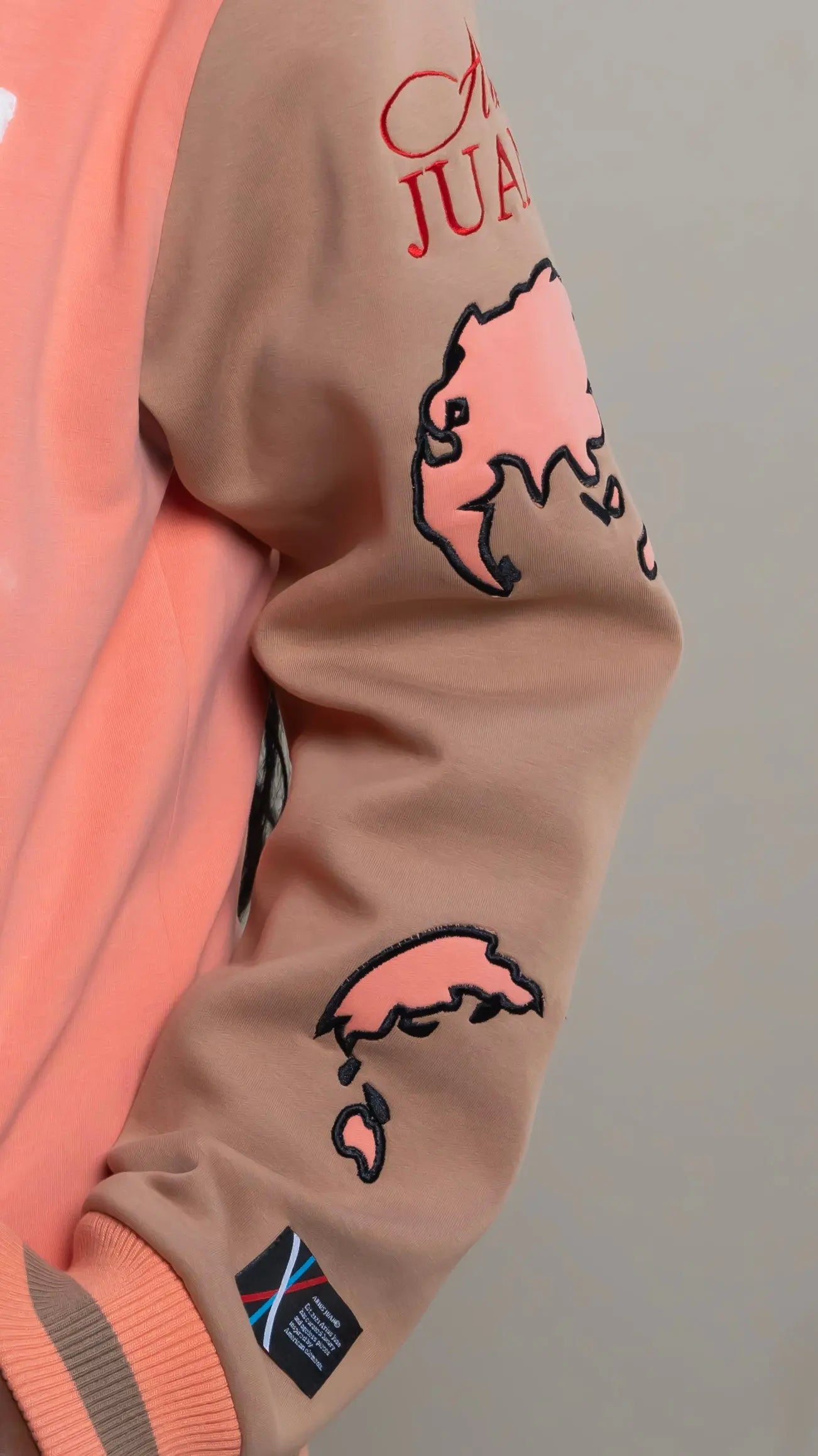 Photo of model in the Arius Juan Salmon Pink Worldly Letterman Jacket posing for product picture.