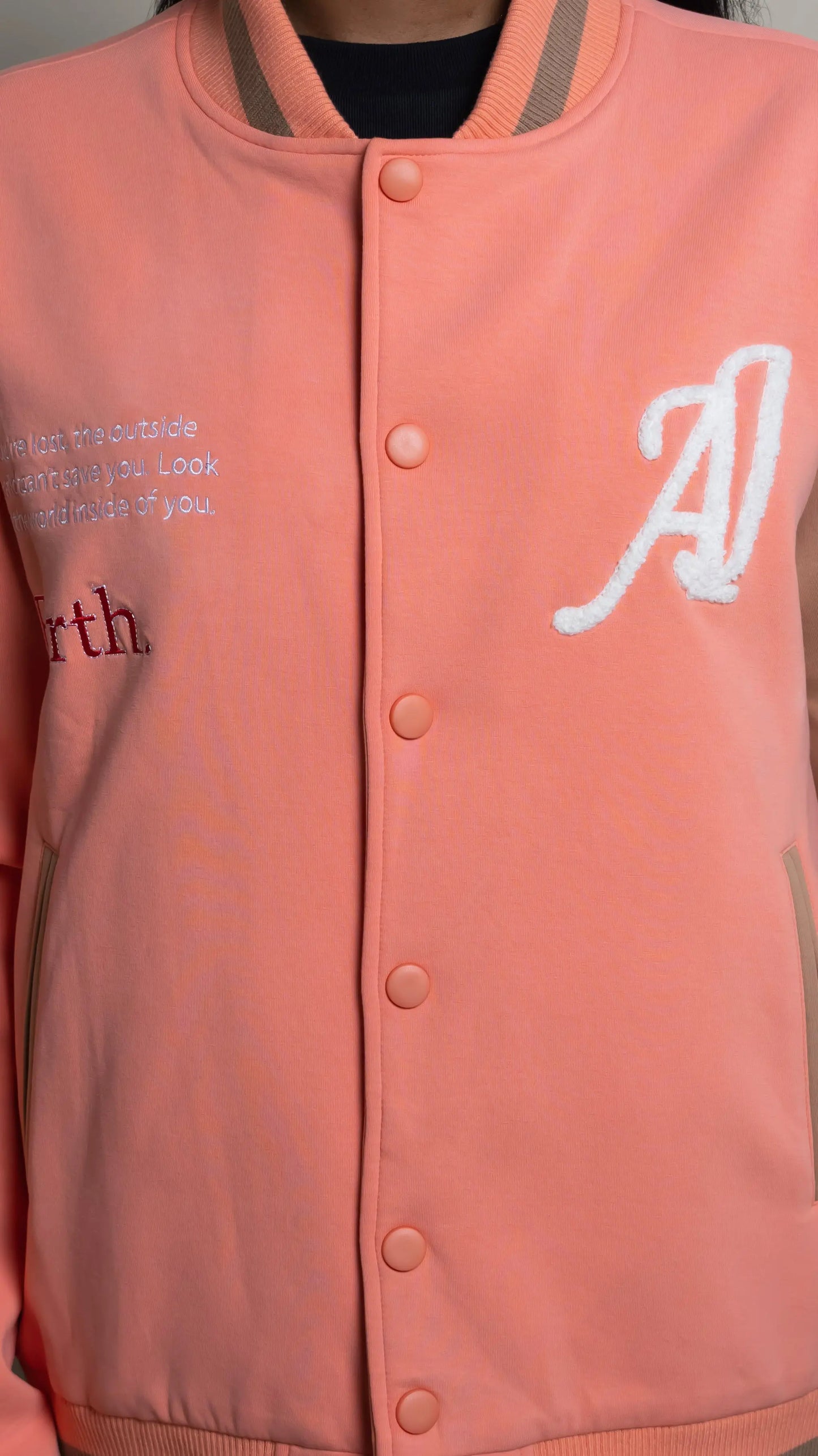 Photo of model in the Arius Juan Salmon Pink Worldly Letterman Jacket posing for product picture.