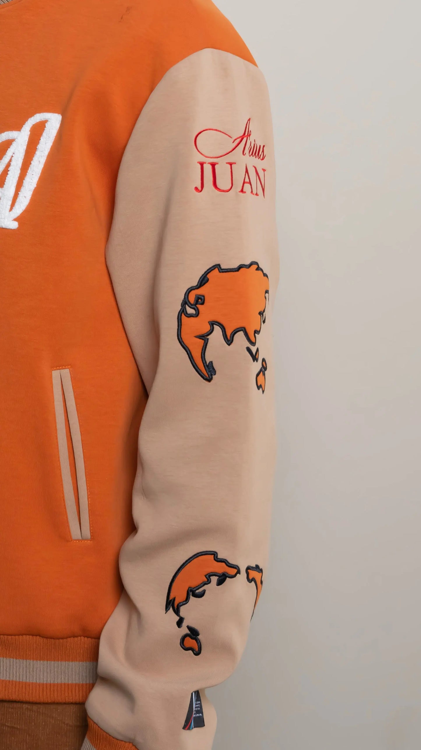 Photo of model in the Arius Juan Burnt Orange Worldly Letterman Jacket posing for product picture.