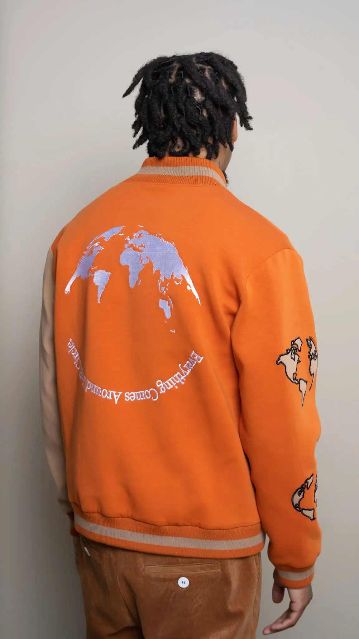 Photo of model in the Arius Juan Burnt Orange Worldly Letterman Jacket posing for product picture.
