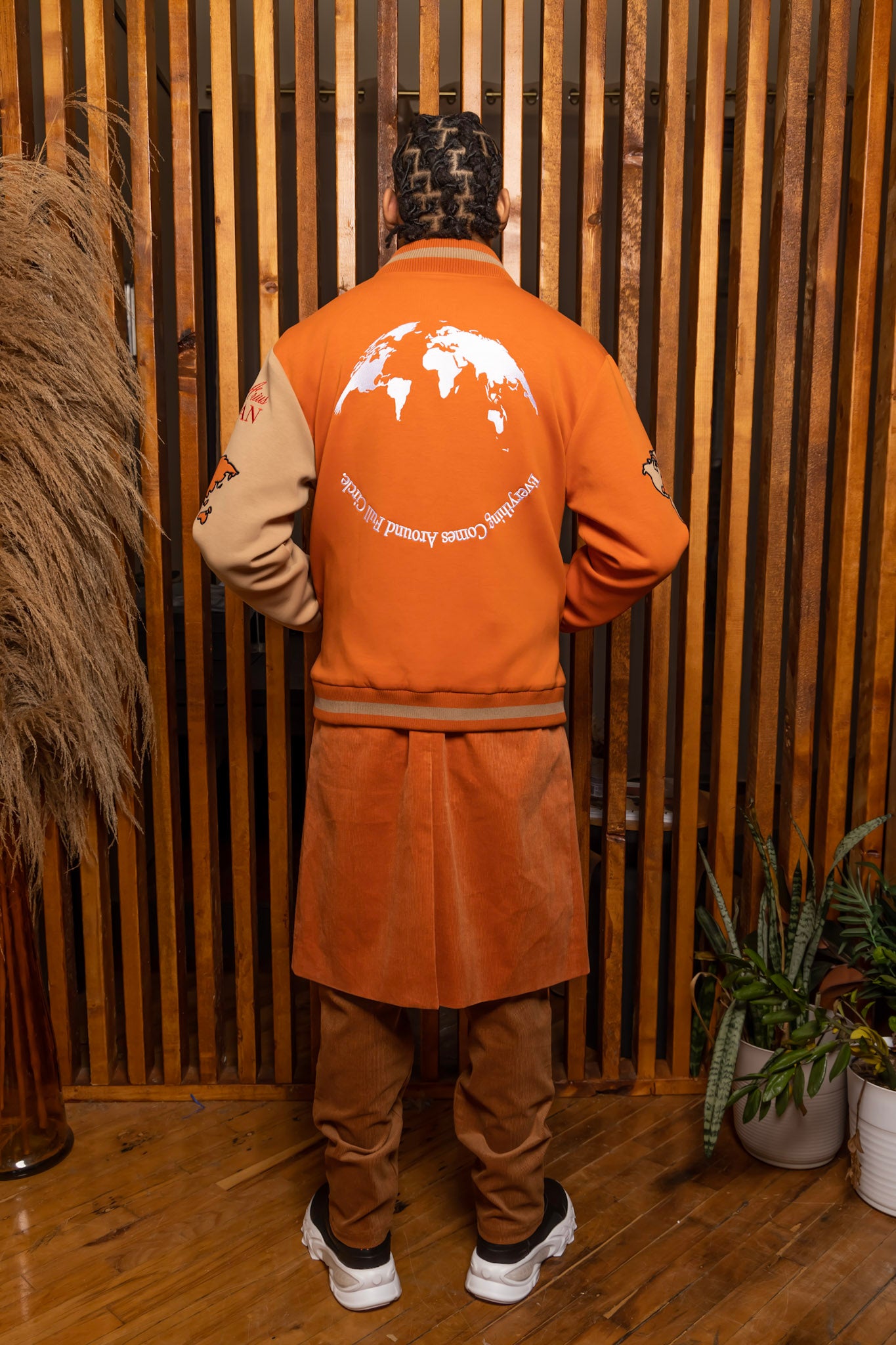 Model wearing Burnt Orange Worldly Letterman Jacket, Burnt Orange Corduroy Trench Coat, Tan NY vs NY Pants, The Third Collection T-Shirt: White in a Arius Juan Campaign.