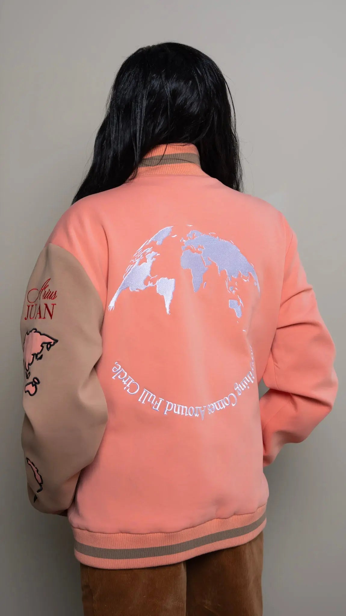 Photo of model in the Arius Juan Salmon Pink Worldly Letterman Jacket posing for product picture.