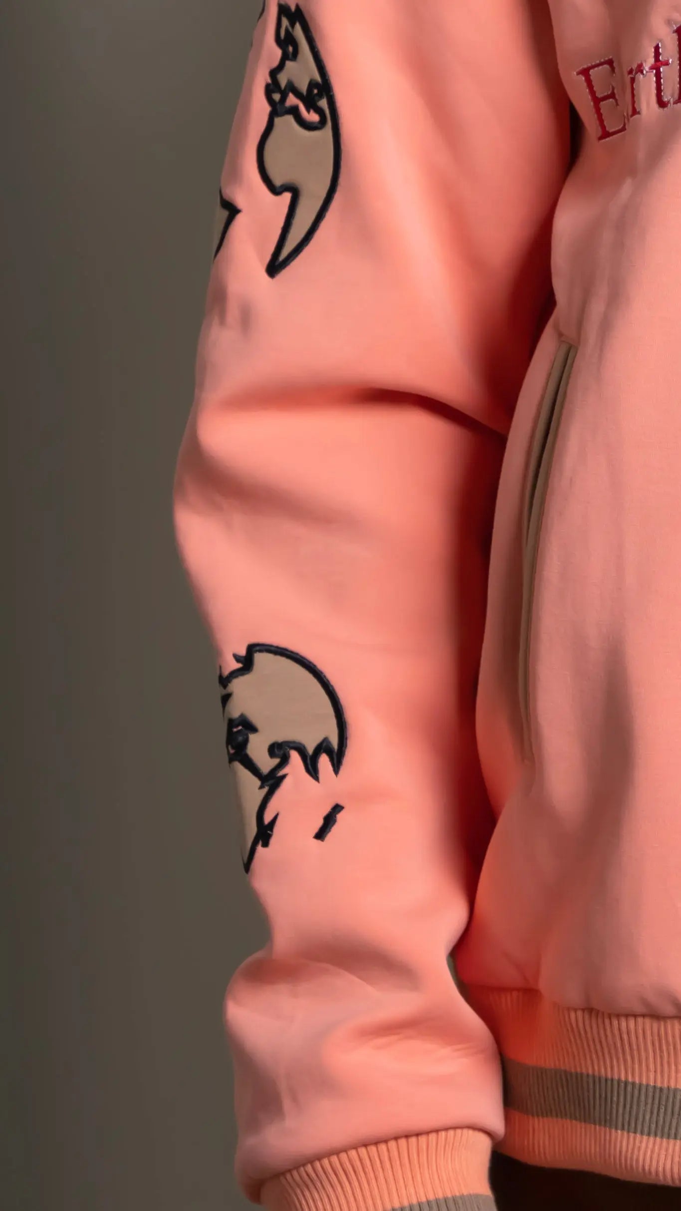 Photo of model in the Arius Juan Salmon Pink Worldly Letterman Jacket posing for product picture.