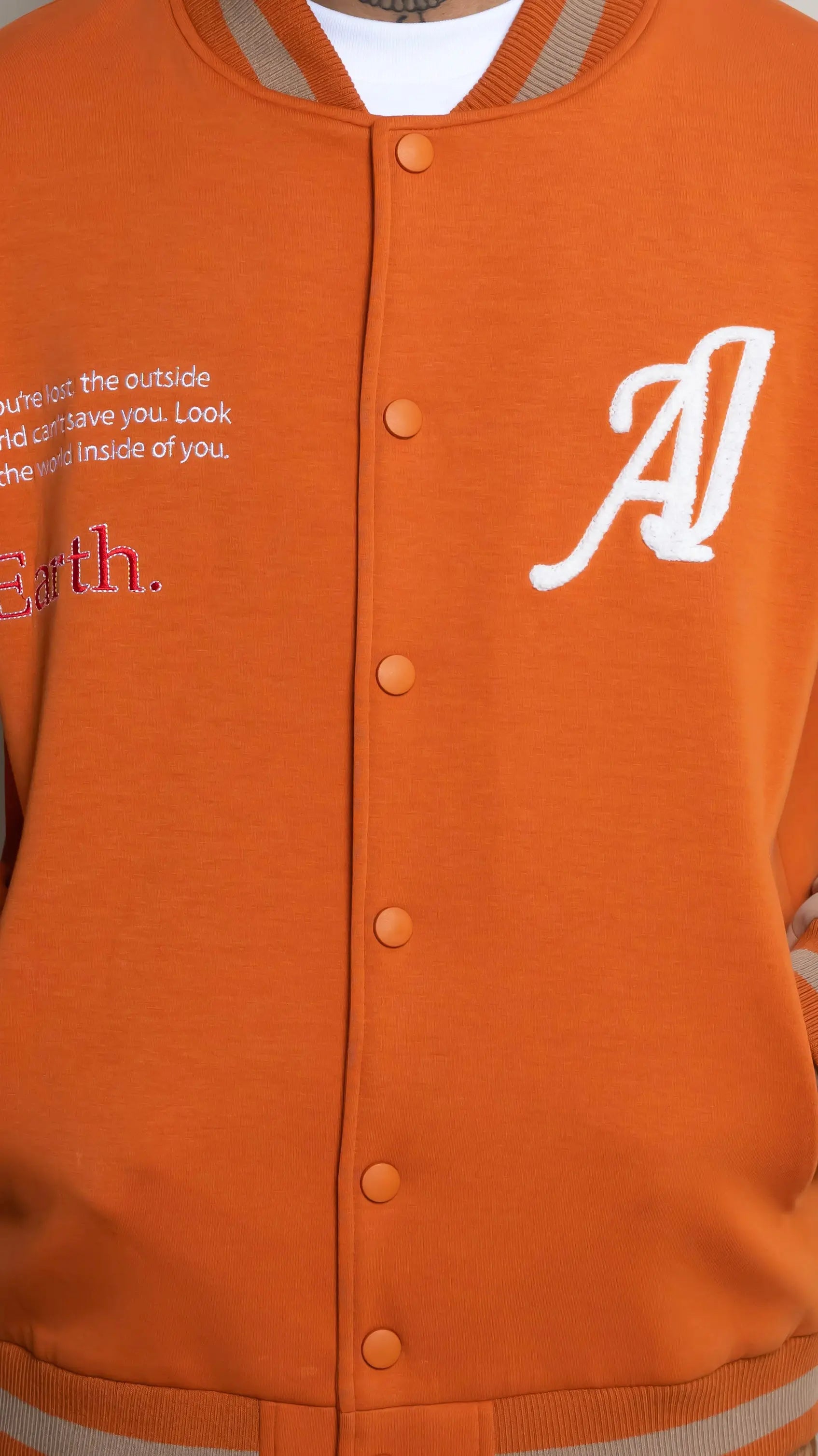 Photo of model in the Arius Juan Burnt Orange Worldly Letterman Jacket posing for product picture.