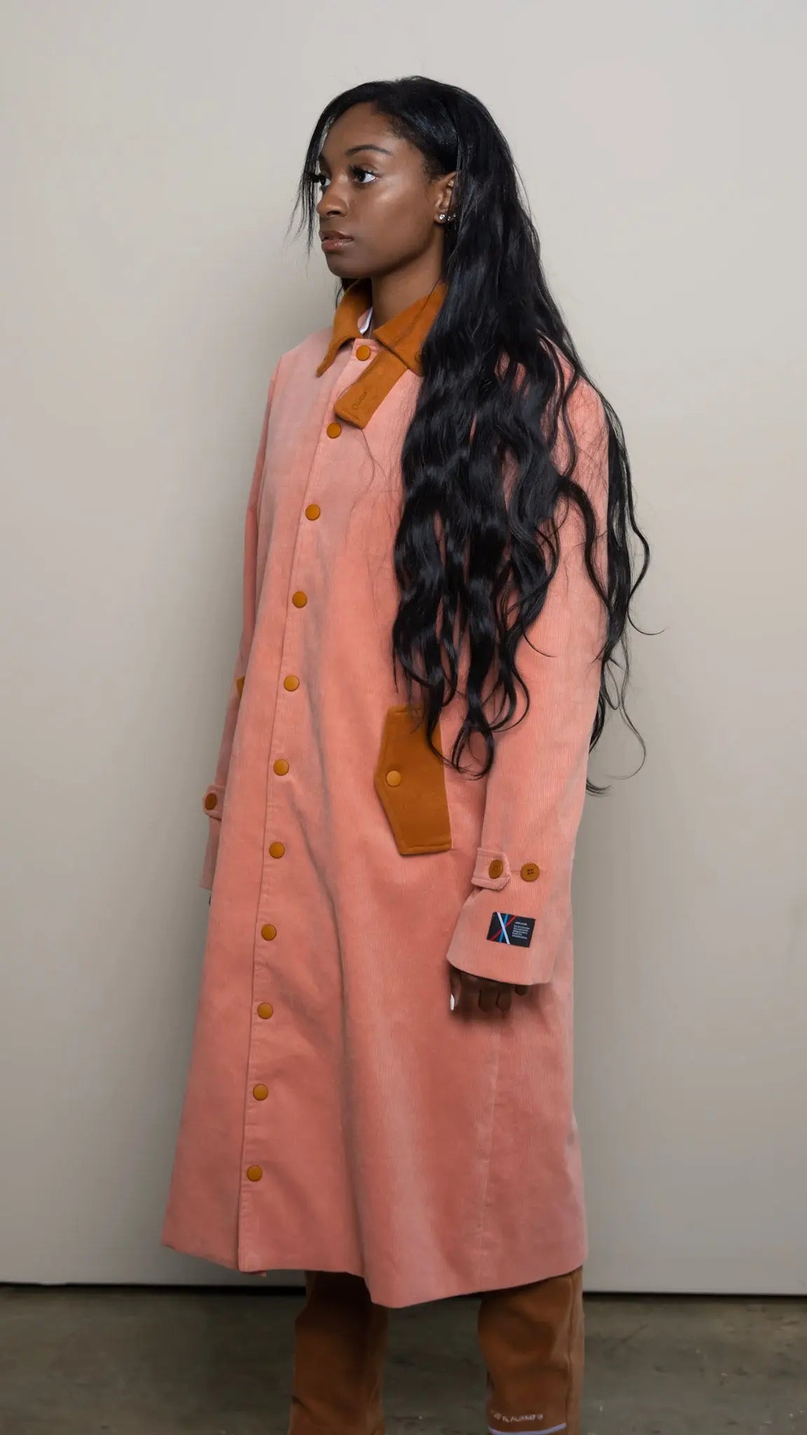 Photo of model in the Arius Juan Salmon Pink Earthly Trench Coat posing for product picture.